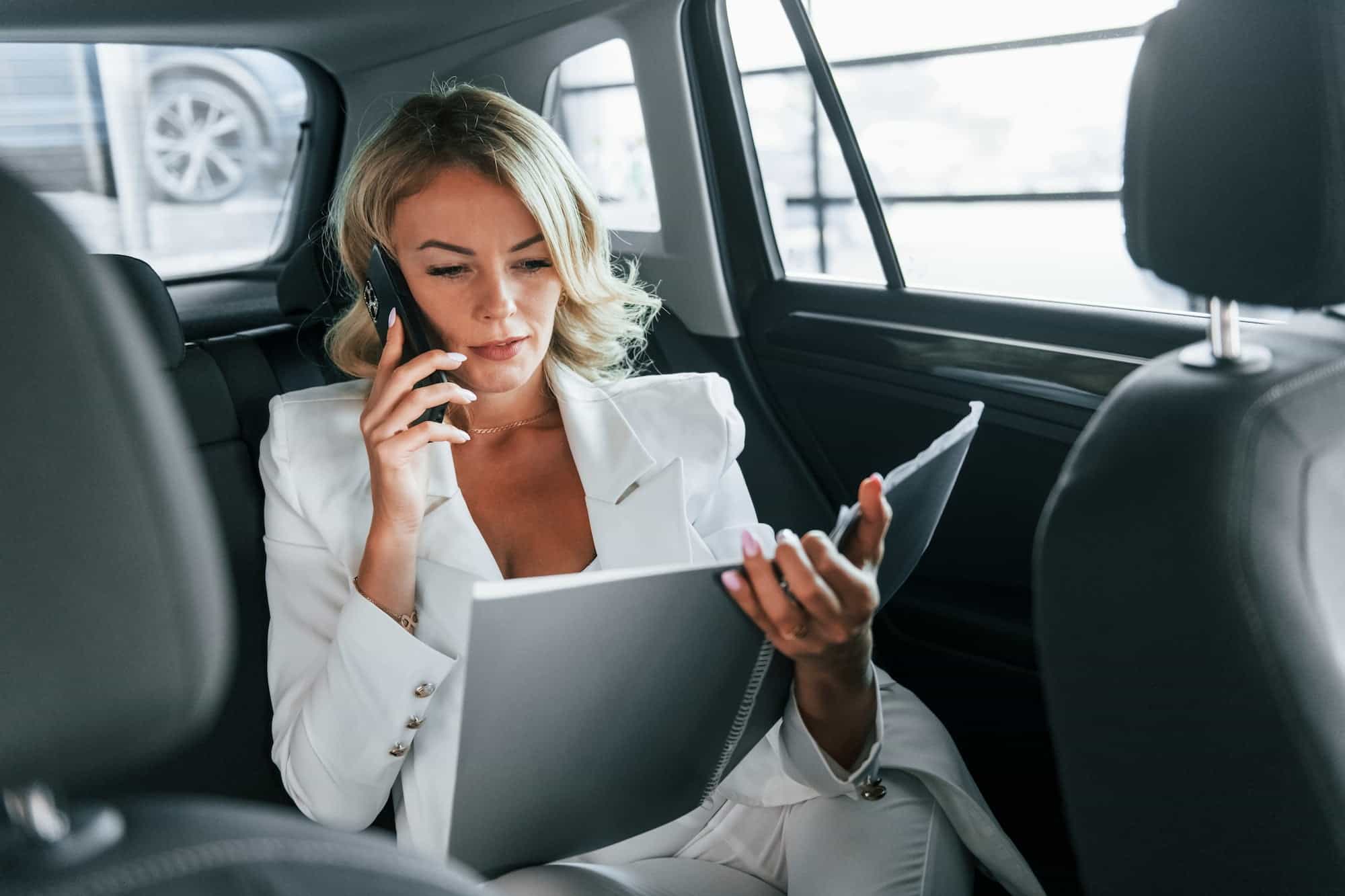 Working in the car. Woman in formal clothes traveling Stress-free between locations in limousine